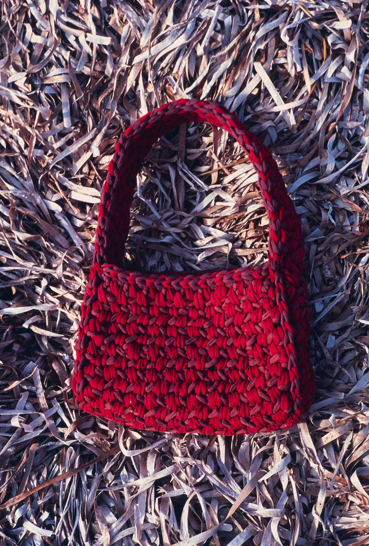 Bolso de ganchillo rojo sobre un lecho de posidónia seca