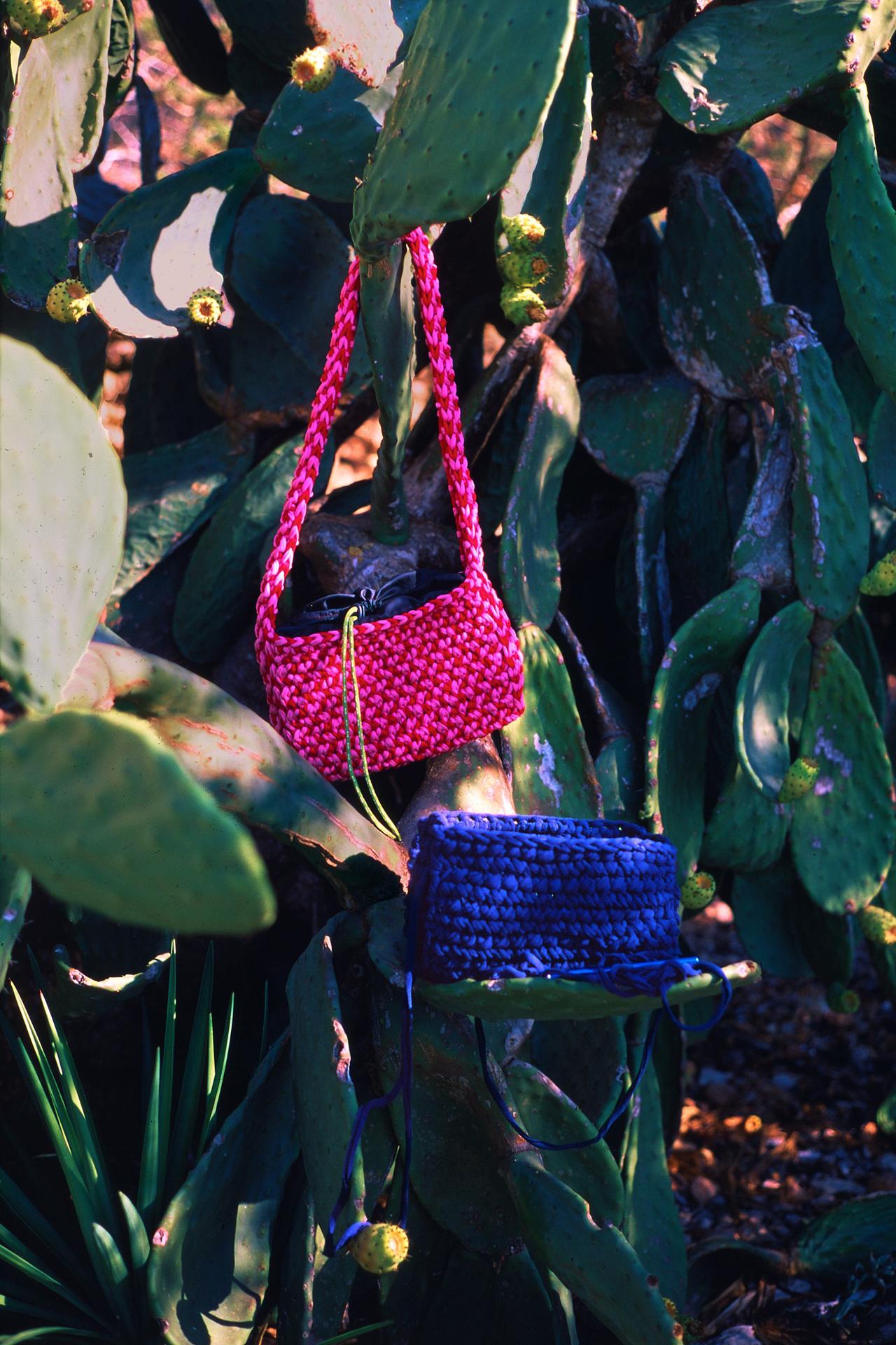 Bolsos de ganchillo fucsia y azul marino colgados de una chumbera con higos