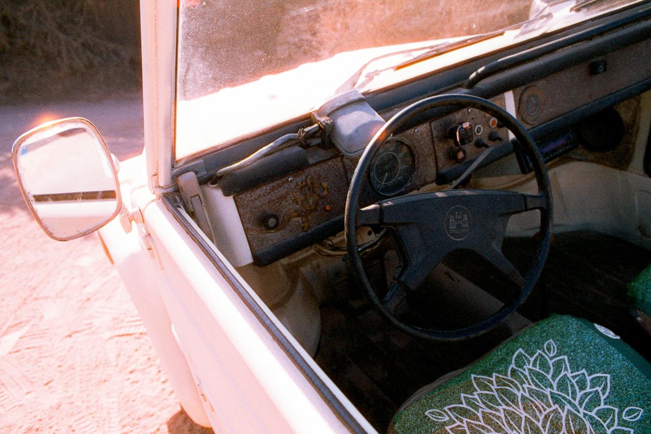 Interior de un coche antiguo descapotable, con el volante negro y un asiento estampado