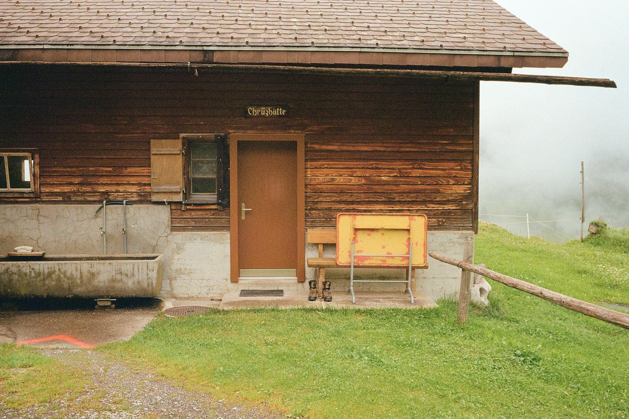 Cabaña de montaña de madera con unas botas junto a la puerta y un banco amarillo