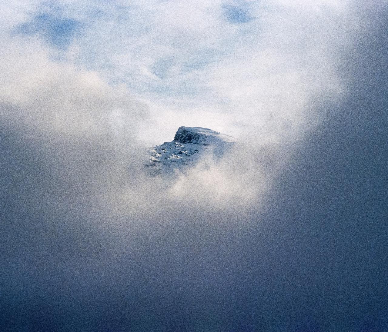 Cumbre nevada asomando entre nubes densas