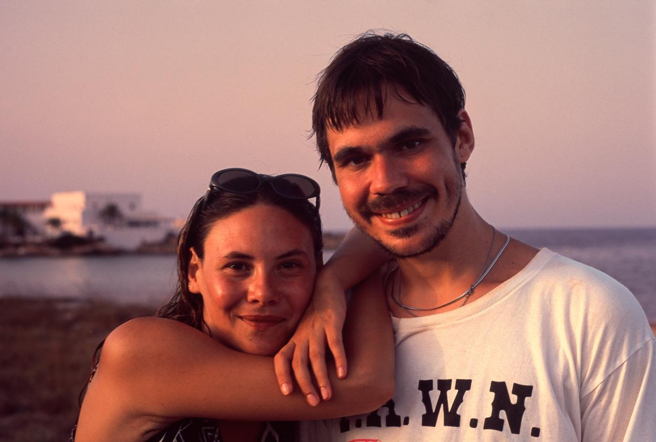 Pareja abrazada y sonriente junto al mar al atardecer