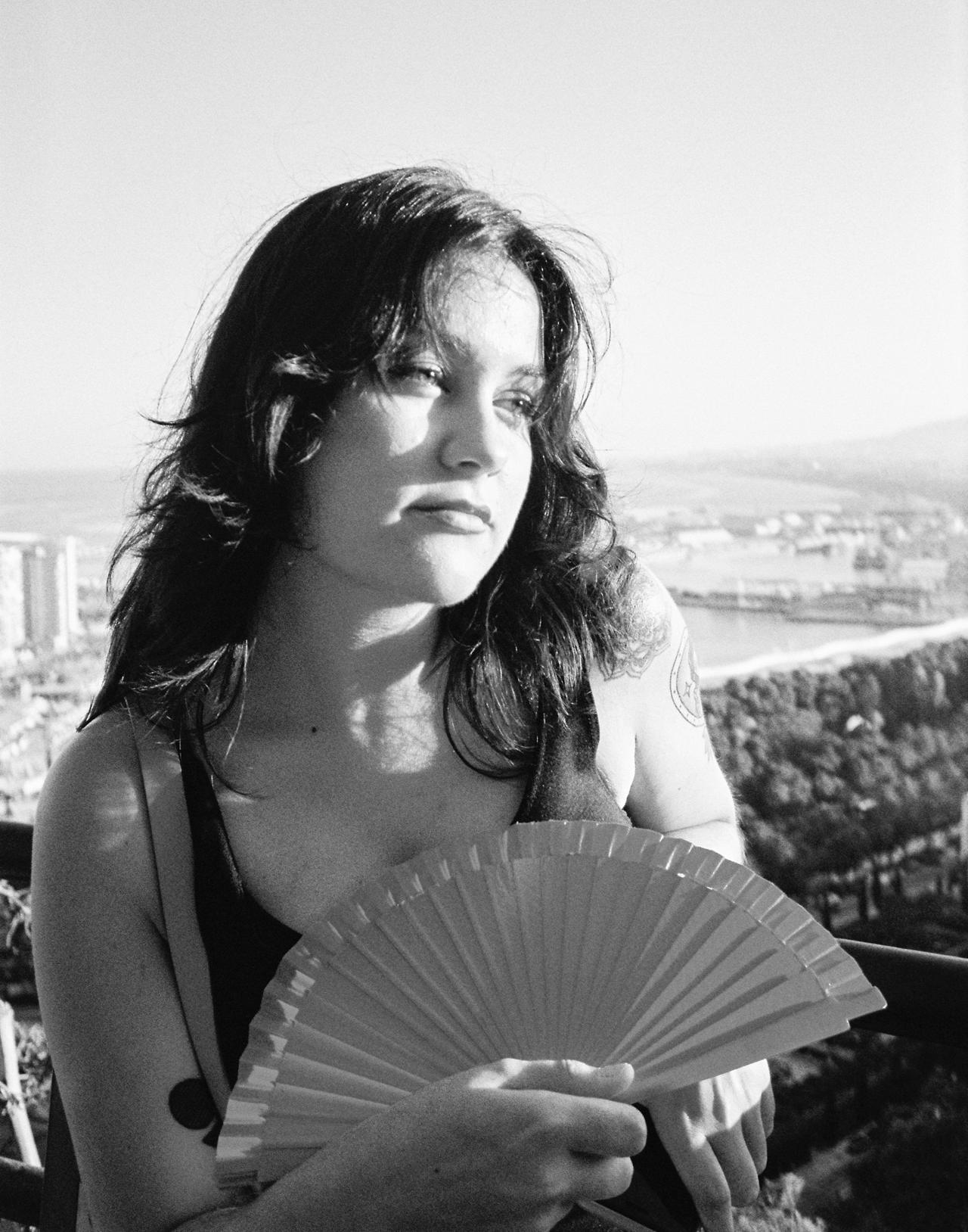 Mujer con un abanico en un mirador sobre la ciudad y el puerto, en blanco y negro