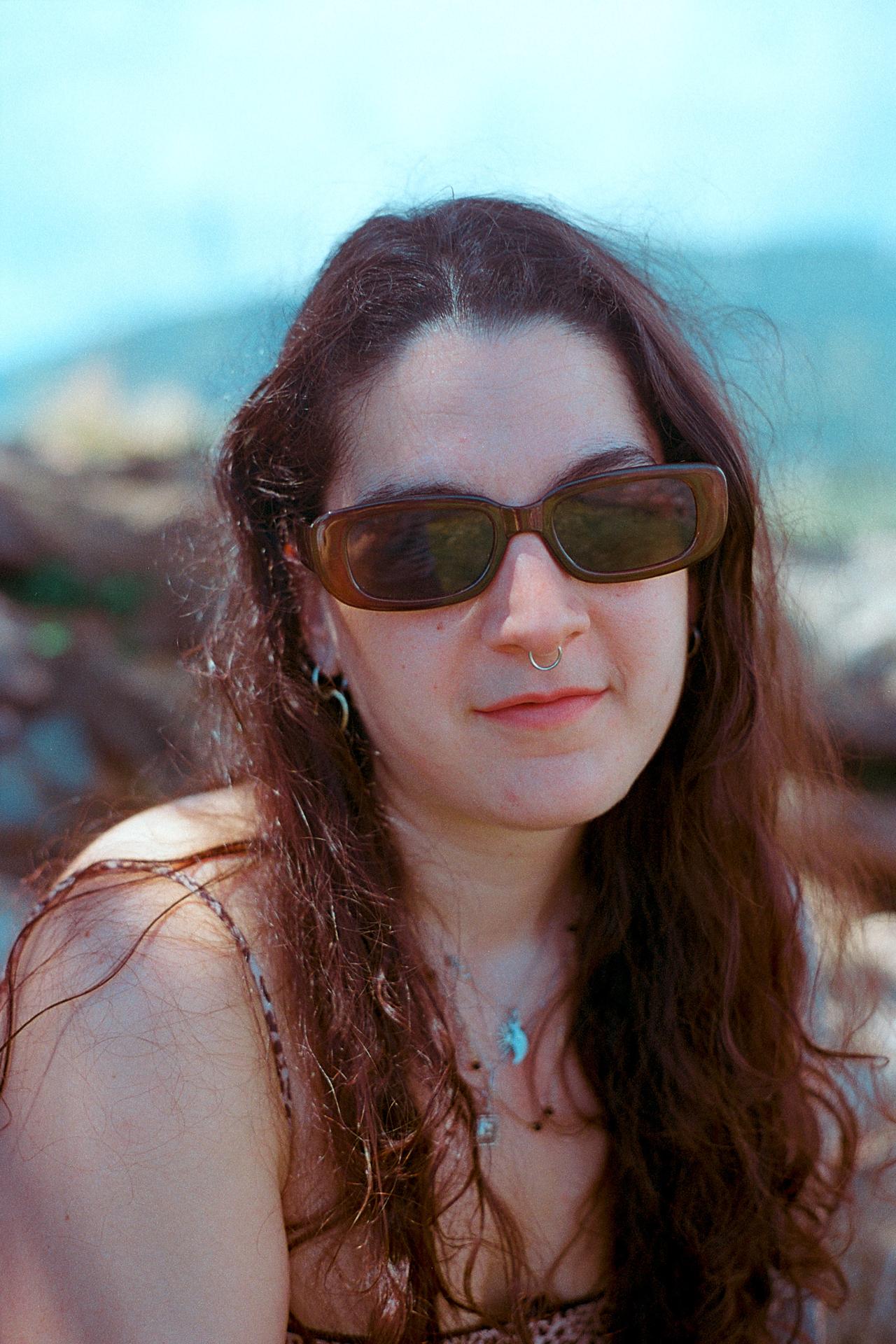 Mujer de pelo largo ondulado con gafas de sol marrones, al aire libre