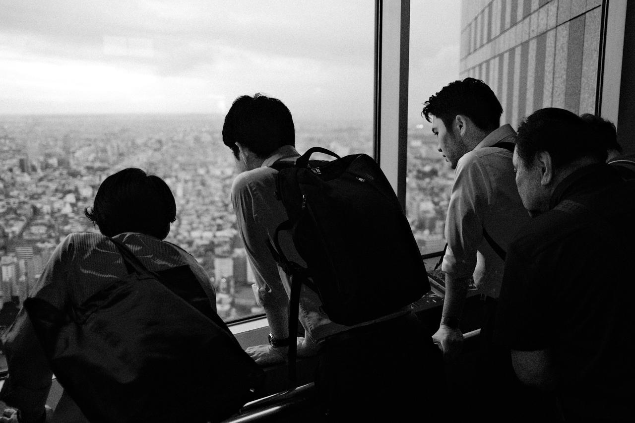 Grupo de visitantes asomados a un ventanal panorámico sobre Tokio